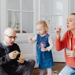 Family enjoying quality time blowing bubbles indoors, capturing joyful moments.